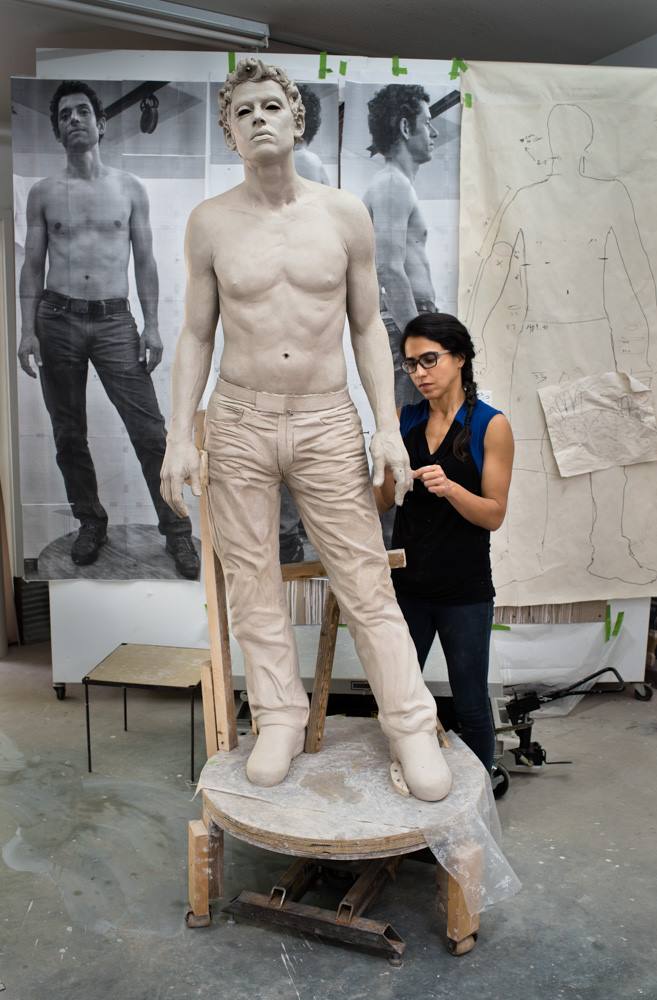Artist working on a larger than life sculpture of a man